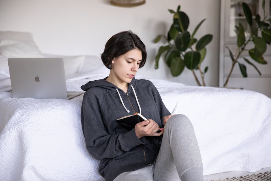 A young person focused on work at a laptop in a cozy room.